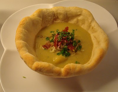 Cremet rodfrugtsuppe med drys af serranoskine og porrer, serveret i brødskåle